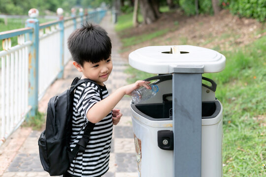 Cute little boy throwing plastic bottle in recycling trash bin at public park, Eco friendly kid Recycling, Save the world & environment concept.