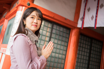 Fototapeta premium 冬の日本の神社で参拝している若い女性