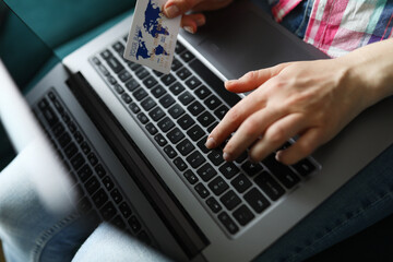 Woman holds credit card and types on laptop keyboard. Online shopping and payments worldwide concept.