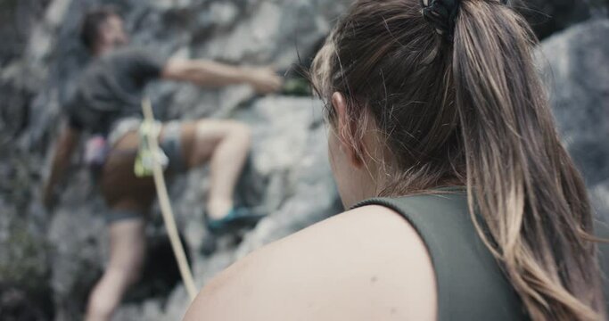 Female climber woman protect rock climb partner for safety belay rope outdoors lifestyle sport in nature close up over shoulder