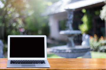 Laptop on the table in garden background.