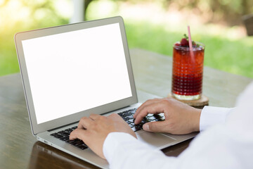 young man working on laptop at garden with berries water in glass.