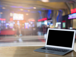 Blank screen laptop computer on wood table top with blur mall with abstract bokeh light defocused background