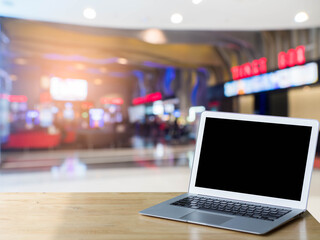 Blank screen laptop computer on wood table top with blur the mall background.