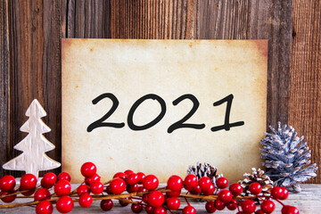 Fototapeta na wymiar Paper With Text 2021 For Happy New Year Greetings. Christmas Decoration And Wooden Background