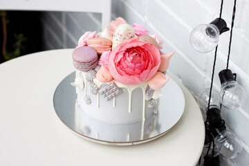 Modern grey cake with pink peony flowers, chocolate and macaroons for a wedding or a celebration. White background.
