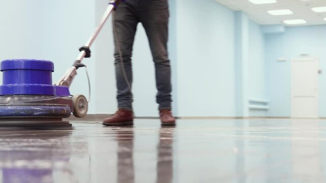 the cleaner washes a pier with a professional polisher machine. Cleaning floor in office building lobby