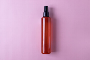 a plastic orange spray bottle on pink