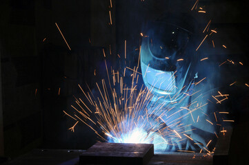 The welder at the factory is engaged in the production of metal structures.