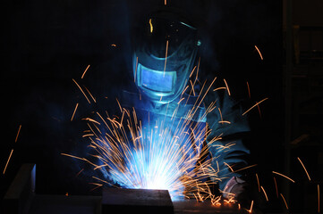The welder at the factory is engaged in the production of metal structures.
