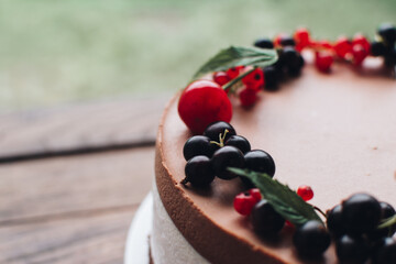 Mousse cake with berries on a wooden table. Chocolate cream cake with currants and cherries. Berry cake for birthday, wedding and other holidays.