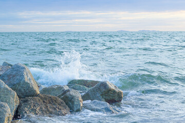 The rocks are lined up with waves in the sea and the sky is clear.