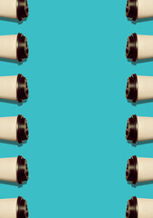 Coffee to go regular vertical pattern made of photo on turquoise background with copy space. Kraft paper cups black lids natural hard shadows. Lifestyle take away hot drinks. Trendy flatlay, top view.