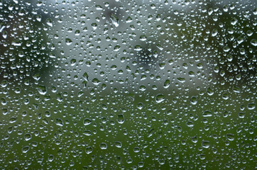 Rain drops on window glasses surface with cloudy background . Natural Pattern of raindrops on cloudy background.