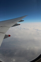 Fototapeta premium Cloud texture and blue sky with wing during sunrise viewed from airplane