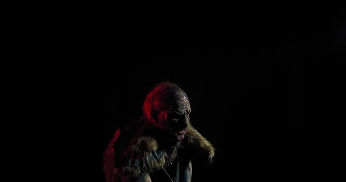 Scary orc with a sword is swinging it in the dark room and screaming, 4k