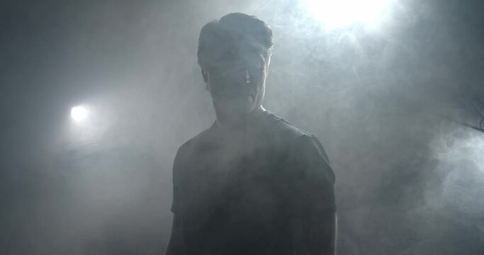 Portrait of an adult man standing in the smoke, silhouette, 4k