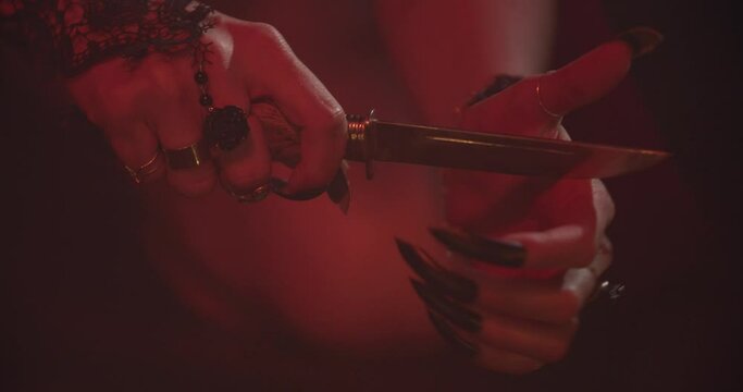 Close up of the hands of a woman doing an occult ritual with a knife, 4k
