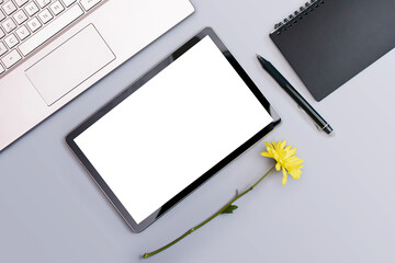 a tablet with a place to insert it lies next to a Notepad and laptop decorated with a flower on a gray background