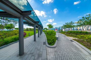 The glass walkways and lawns of the modern park in the city center are under the blue sky and white clouds.