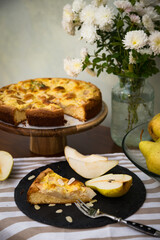 Slice of homemade pear pie and sliced fresh pear on black plate