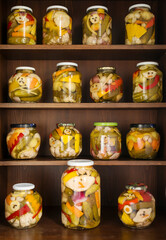 Fototapeta na wymiar Home Canning of Summer Vegetables Stored on Wooden Shelves. Grandmother's home makings - variety of canned vegetable lined up in rows of glass jars