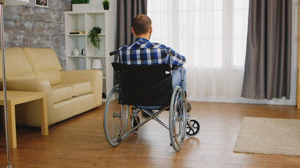Back view of man with walking disability sitting on wheelchair.