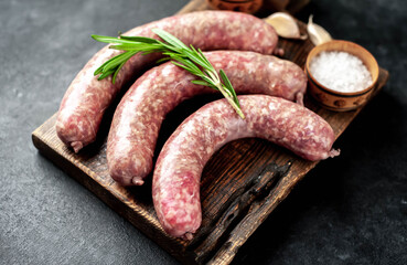 raw sausages with spices and rosemary on a stone background