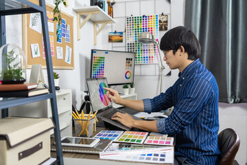 Fototapeta premium Asian men Architect or graphic designer designing a layout selection swatch samples for coloring screen