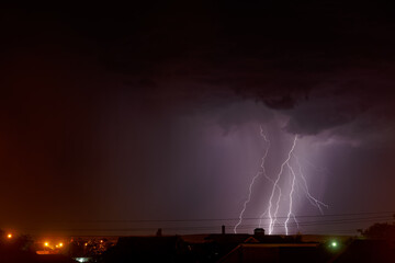 Lightning flashes in the night cloudy sky over the city. Storm.