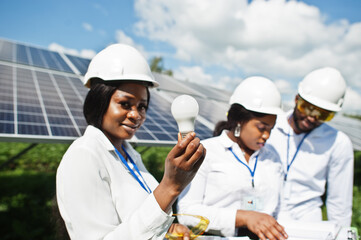 African american technician checks the maintenance of the solar panels. Group of three black engineers meeting at solar station.