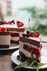 Mousse cake with berries on a wooden table. Chocolate cream cake with currants and cherries. Berry cake for birthday, wedding and other holidays.