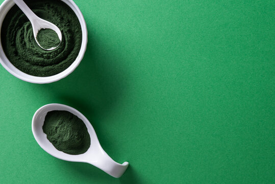 Bowls with chlorella or spirulina powder on green