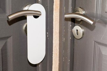 Sign on grey door hanger white handle with empty plate do not disturb