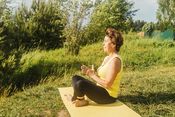 Senior woman making yoga and fitness outdoor in summer. Lockdown concept, sport alone.