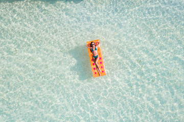 Top above high angle aerial drone view of fit slim thin slender attractive girl floating on rubber mattress clear sea water leisure sunny weather taking sun bath spending celebrating birthday weekend