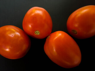 Natural tomatoes on a dark background. Top view with food background, black stone table, copy space.