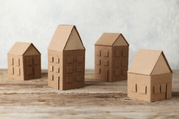 Cardboard toy houses on wooden background. Sale or rental of housing. Neighbors in house. Comfortable life in suburbs.