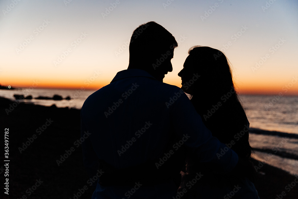 Wall mural loving couple in white clothes during a honeymoon at sea walk on the sand at a photoshoot love story