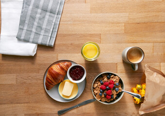 Overhead Flat Lay Shot Of Table Laid For Breakfast With Cereal Croissant And Flowers