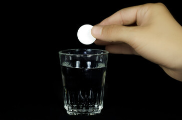 dropping water dissolve medical pill into the water / isolated black background