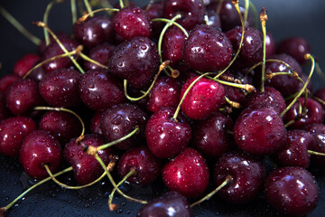 Red fresh cherries on a black background. Drop of water. Close up. The concept of freshness.