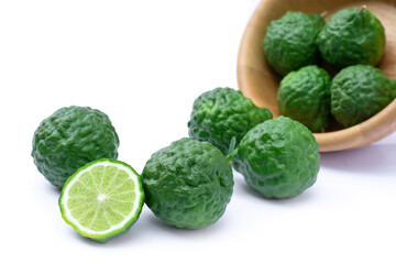 Fototapeta premium Bergamot or kaffir lime fruits with green leaf in wooden bowl isolated on white background. 