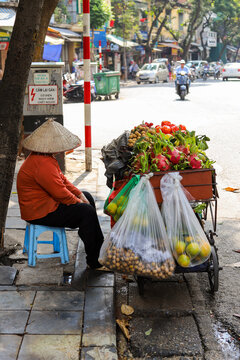 Woman wearing a asian hat selling the fruits