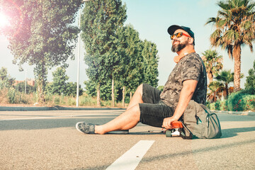 Curvy man in shorts sitting on a skateboard smiling. © Sergi