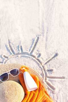 Sand Texture With Hat, Towel, Sunscreen And Sunglasses On The A Beach.