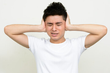 Fototapeta na wymiar Portrait of stressed young Asian man covering ears