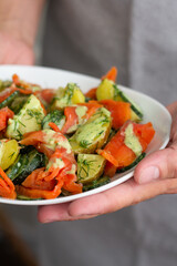 hand holding a plate with vegetables