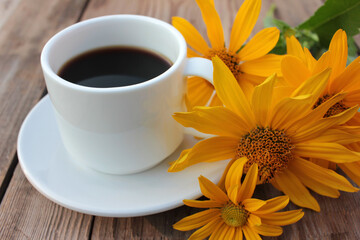Сup of coffee and yellow flowers on wooden table. Summer lifestyle