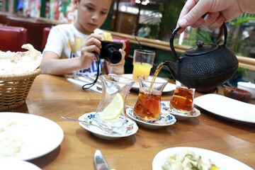 Child takes pictures of how person pours tea